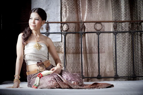 Gorgeous asian woman in thai dress lying on bed — Stock Photo, Image