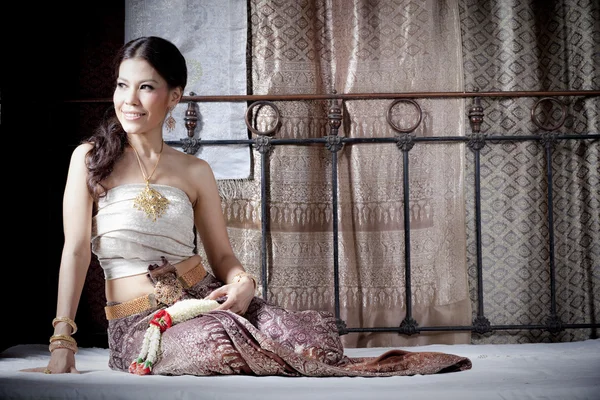 Gorgeous asian woman in thai dress lying on bed — Stock Photo, Image