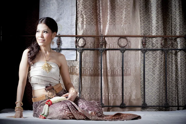 Linda mulher asiática em tailandês vestido deitado na cama — Fotografia de Stock