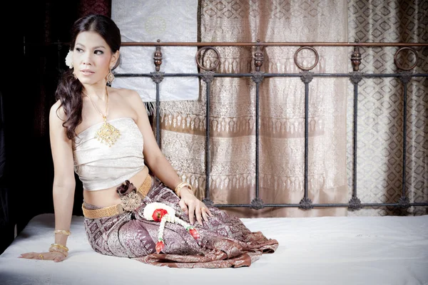 Gorgeous asian woman in thai dress lying on bed — Stock Photo, Image