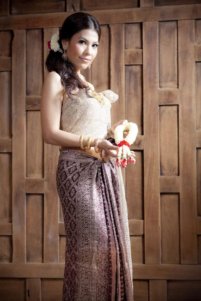 Retrato lindo ásia mulher no tailandês vestido perto de madeira parede — Fotografia de Stock