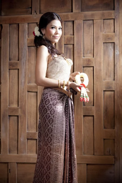 Portrét krásné asijské ženy v šatech thajský dřevěné stěny — Stock fotografie