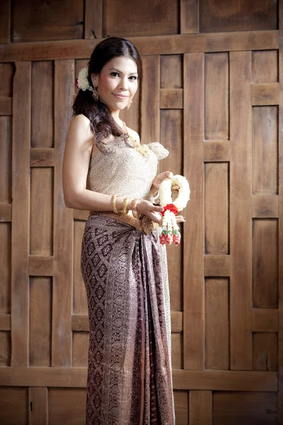 Portret prachtige Aziatische vrouw in Thaise jurk in de buurt van houten muur — Stockfoto