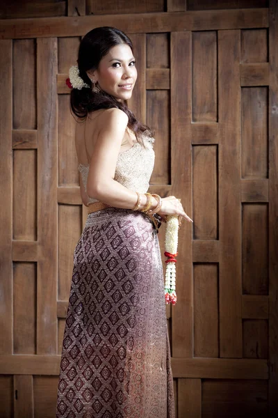 Retrato lindo ásia mulher no tailandês vestido perto de madeira parede — Fotografia de Stock