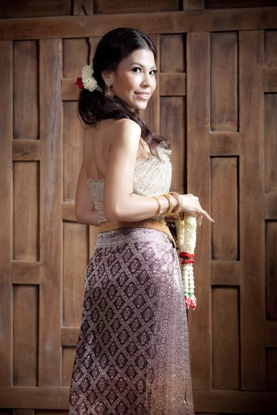 Портрет Чудова азіатська жінка в тайській сукні біля дерев'яної стіни — стокове фото