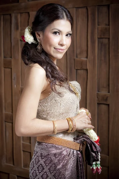 Portret przepiękny azjatyckie kobiety w sukienka tajski w pobliżu ściany drewniane — Zdjęcie stockowe