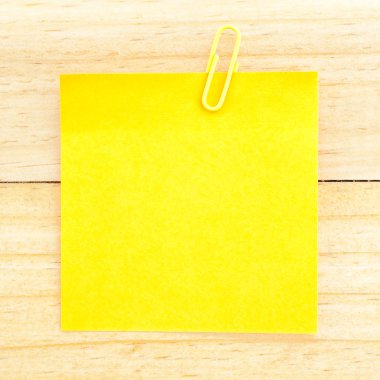 Sarı boş kağıt ahşap arka plan üzerinde klibi