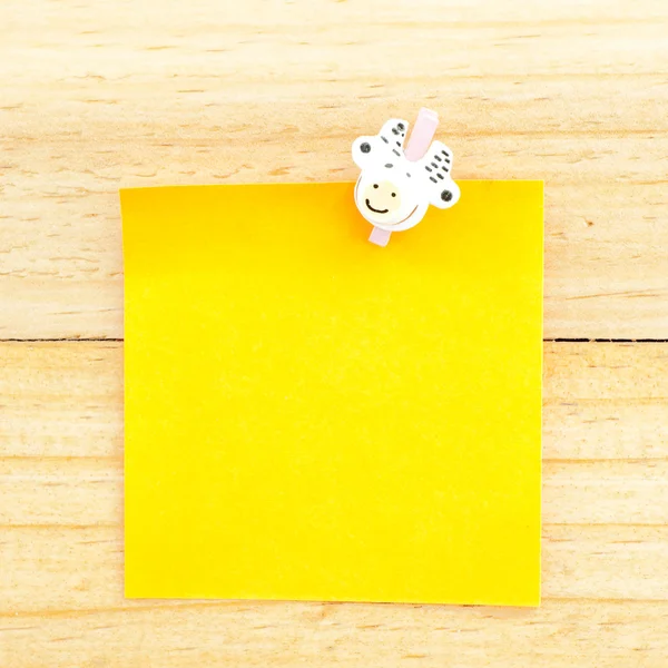 Yellow blank paper with the clip on the wooden background — Stock Photo, Image