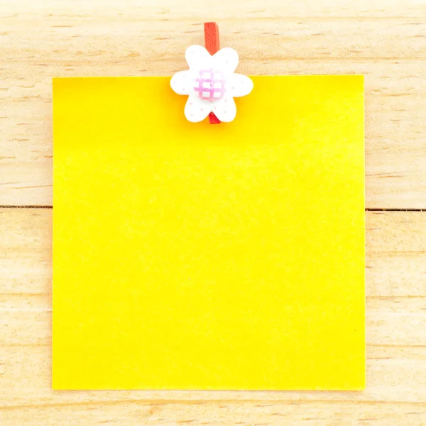 Yellow blank paper with the clip on the wooden background — Stock Photo, Image