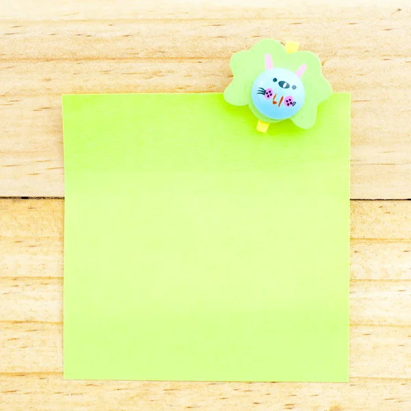 Green blank paper with the clip on the wooden background — Stock Photo, Image