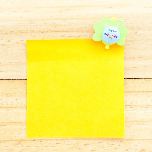 Yellow blank paper with the clip on the wooden background — Stock Photo, Image