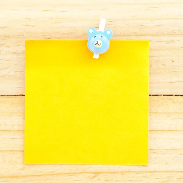 Carta bianca gialla con la clip sullo sfondo di legno — Foto Stock