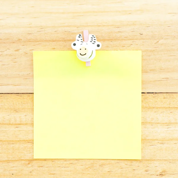 Yellow blank paper with the clip on the wooden background — Stock Photo, Image