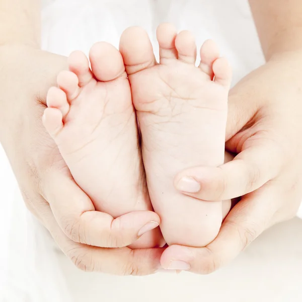 Mãe segurar bebê perna juntos em sua mão — Fotografia de Stock