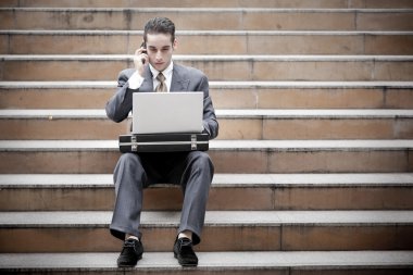 telefon olan ve dizüstü kullanarak yakışıklı işadamı