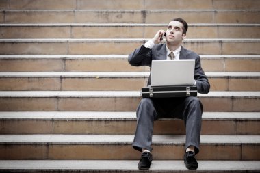 telefon olan ve dizüstü kullanarak yakışıklı işadamı
