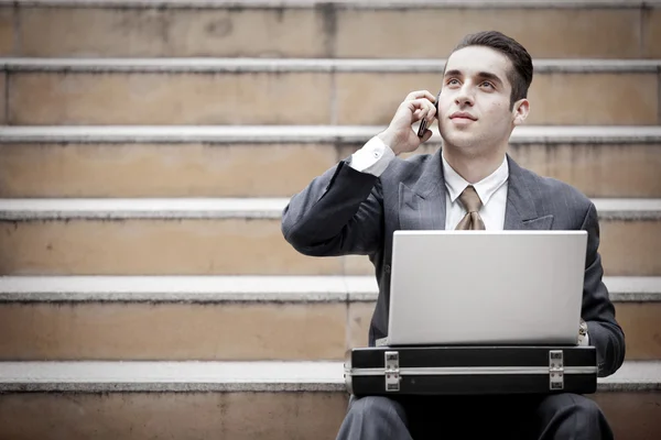 Schöner Geschäftsmann, der telefoniert und Laptop benutzt — Stockfoto