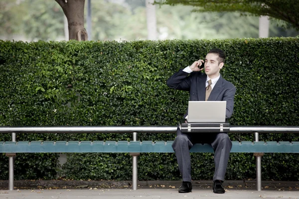 Empresario hablando por teléfono y usando laptop — Foto de Stock
