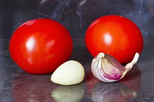 Tomatoes and garlic on a dark background — Stock Photo, Image