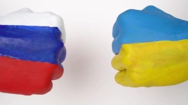 Ukrayna ve Rusya 'nın bayrakları beyaz arka planda el ele tutuşuyor, Ukrayna Rusya' ya karşı dünya savaşı krizi kavramında. Yumruklar rakipleri bayraklar.