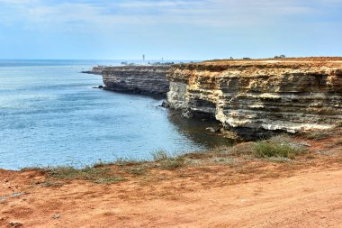 Sarı, beyaz kayalık deniz kıyısı, Chalky uçurumu. Mavi, derin, sakin deniz. Sakin mavi gökyüzü. Beyaz deniz feneri. Kırım 'ın batı kısmı, Tarkhankut Burnu. Taş deseni. Güzel doğal manzara.