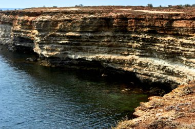 Sarı kayalık deniz kıyısı, Cliff. Mavi, derin, sakin deniz. Dalgalanan denizin en üst görüntüsü. Kırım 'ın batı kısmı, Tarkhankut Burnu. Taş deseni. Güzel doğal manzara.