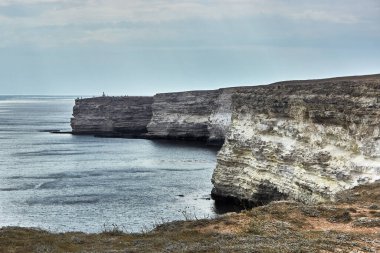 Deniz kenarında bir pelerin. Deniz manzarası, ufuk, sakin mavi deniz. Chalk rock, Cape Tarkhankut, Kırım. Beyaz taşın doğal dokusu. Kötü hava, yaklaşan bulutlar, bulutların ardında batan güneş..