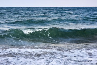Öfkeli deniz. Denizde fırtına dalgaları. Karanlık deniz, parlak beyaz deniz köpüğüyle güçlü dalgalar. Soyut doğal arkaplan. Deniz kötü havada..