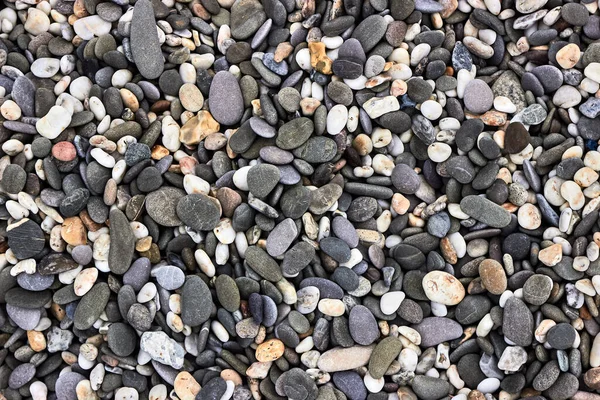 Deniz çakıl taşlarının arka planı, üst manzara. Deniz taşlarının dokusu. Gri-sarı, denizde beyaz taşlar. Doğal malzemeler ve deniz taşlarının renkleri. Yatay fotoğraf.