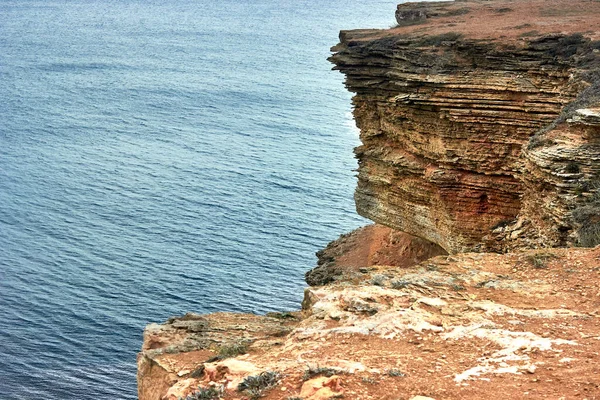 Sarı kayalık deniz kıyısı, Cliff. Mavi, derin, sakin deniz. Dalgalanan denizin en üst görüntüsü. Kırım 'ın batı kısmı, Tarkhankut Burnu. Güzel doğal manzara. Doğal taş deseni.