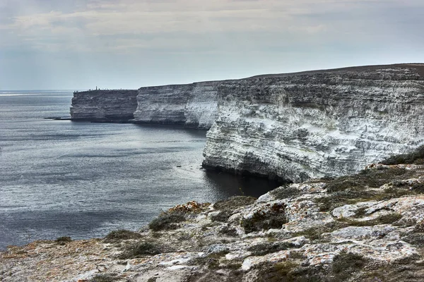 Deniz kenarında bir pelerin. Deniz burnu, ufuk, sakin mavi deniz, bulutlu. Chalk rock, Cape Tarkhankut, Kırım. Beyaz taşın doğal dokusu.