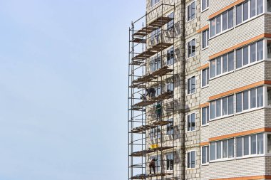 Construction of a multi-storey residential building. Construction and installation works. Dangerous work. Builders work without means of protection, insurance. Installation of scaffolding. Russia, Voronezh. 29.03.2020. clipart