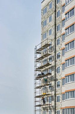 İskelenin kurulumu. İnşaatçılar koruma ve sigorta olmadan çalışırlar. İnşaat ve montaj işe yarıyor. Tehlikeli bir iş. Çok katlı bir konut inşaatı. Rusya, Voronezh. 29.03.2020. Şehir manzarası.