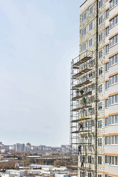 Construction and installation works. Dangerous work. Installation of scaffolding. Builders work without means of protection, insurance. Construction of a multi-storey residential building. Russia, Voronezh. 29.03.2020. View from the height of the cit