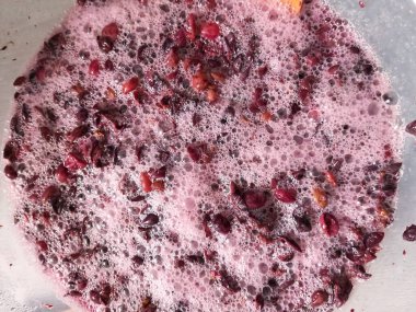 One of the stages of making wine, wine vinegar. Crushed purple grapes with juice during fermentation at home. Foam with bubbles on the surface of the juice.