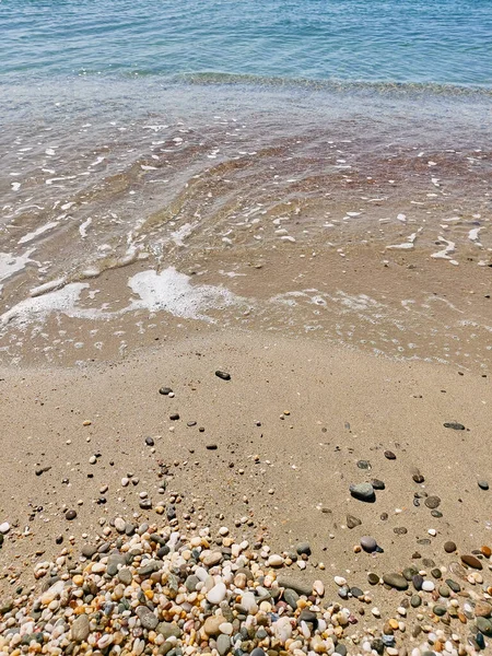 Sea pebbles, blue sea, waves, bright sun. Top view. Marine background. Landscape wallpaper and nature concept. Abstract style for text, design, fashion, agencies, websites, bloggers, publications.