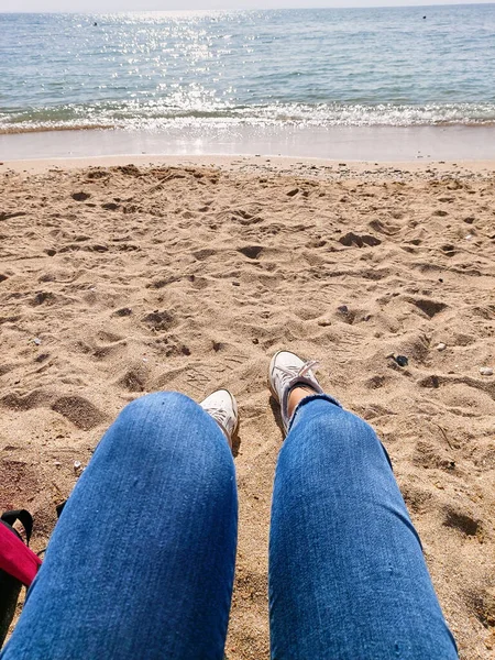 Woman Sitting Seashore Woman Legs White Sneakers Jeans Yellow Sand — Stockfoto