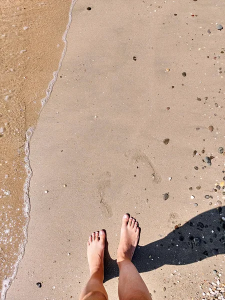 Woman legs barefoot at sea sand beach summer day. Top view above women feet. Footprints. Ocean clear water seafoam. 