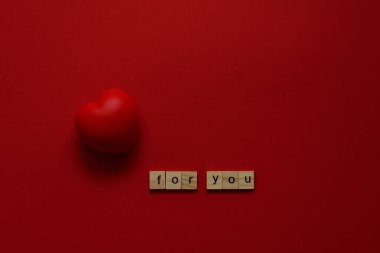 Kırmızı zemin üzerinde iki kırmızı kalp ve sizin için ahşap harfler destek, sevgi, sevgililer günü veya karantinada 14 Şubat. Düz yatış, üst görünüm seçici odaklanma..