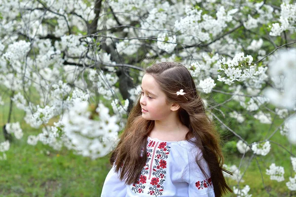 桜の庭で伝統的な刺繍のシャツを着た女の子 ハッピーイースターの日 キリスト教の伝統 スペースをコピーします — ストック写真