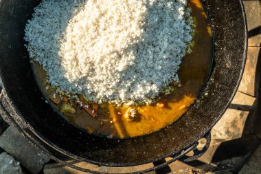Bir kazanda, ateşte yemek pişirmek. Geleneksel Asya yemekleri pilavdır. Soğan, yağ, havuç, et ve baharattan yapılan Zirvak. Pirinçle karıştırılmış. Bir kazanda, bir ateşin üzerinde hazır. Huş ağacı yakacak. - Rusya. İyi günler. Yaz.