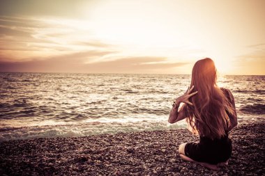 Günbatımı arka planında ince bir kızın silueti. Güneş denizin ufkundan batıyor. İyi akşamlar, hafif bir esinti ve kıyıda genç bir bayan. Tüylerim diken diken oldu. - Rusya. İyi günler. Yaz.