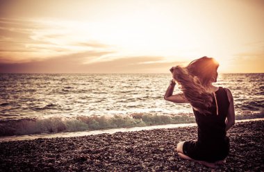 Günbatımı arka planında ince bir kızın silueti. Güneş denizin ufkundan batıyor. İyi akşamlar, hafif bir esinti ve kıyıda genç bir bayan. Tüylerim diken diken oldu. - Rusya. İyi günler. Yaz.