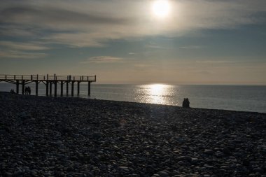 Denizin üzerinde gün batımı. İskeleden panorama. Çakıl taşı sahili. İnsanlar günü göremiyor. Karadeniz. Georgia.