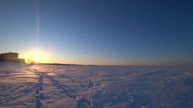 Körfezde donmuş su. Deniz yüzeyinde buz ve kar. İnsanlar aktif olarak buz üzerinde dinleniyor ve paraşütle atlıyorlar. İyi günler. Kış. Rusya.