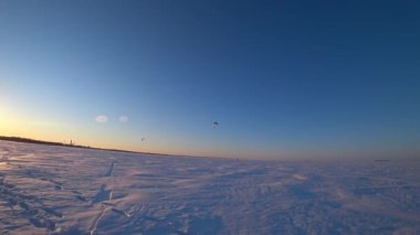 Körfezde donmuş su. Deniz yüzeyinde buz ve kar. İnsanlar aktif olarak buz üzerinde dinleniyor ve paraşütle atlıyorlar. İyi günler. Kış. Rusya.