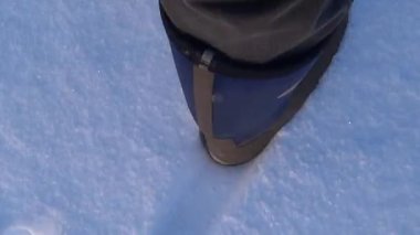 Bir adam karda yürür. Pantolon ve botların içindeki bacaklar kış parkında adım atar. Güneşli, Ocak günü. İyi günler. - Rusya. Kış.