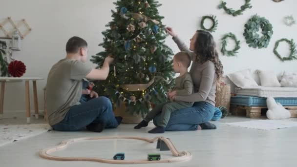 Young Family of Four Sitting near Christmas Tree — Stock Footage Young Family of Four Sitting near Christmas Tree Royalty Free Stock Video