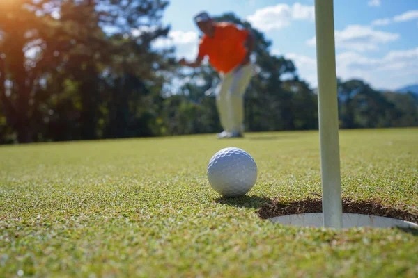 緑のゴルフにボールを入れてゴルファー 太陽の下でレンズフレアは夜の時間を設定します 長い穴にゴルフボールを入れて後に勝つためにゴルファーのアクション — ストック写真