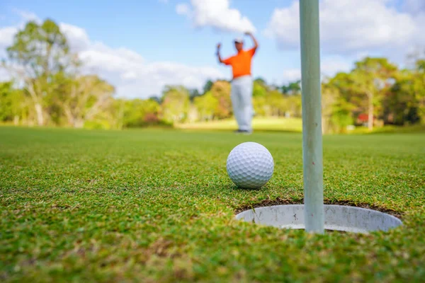 高尔夫球手把球放在绿色的高尔夫球上 夕阳西下时镜头闪现 高尔夫球手把高尔夫球打进洞里很长时间后 打高尔夫球获胜的动作 — 图库照片